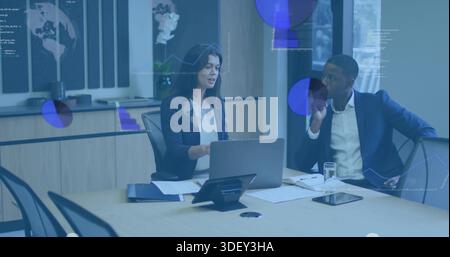 Working mid-adult woman typing on laptop at meeting table, in business attire, with data overlays Stock Photo