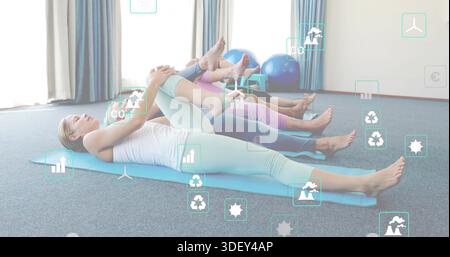 Stretching four adults hugging knees in carpeted exercise studio, white tank, blue stability balls Stock Photo