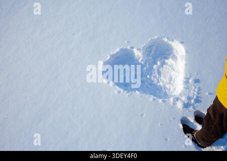 Heart shaped imprint in fresh snow with copy space a minimal winter love background for Valentine cards and seasonal marketing Stock Photo