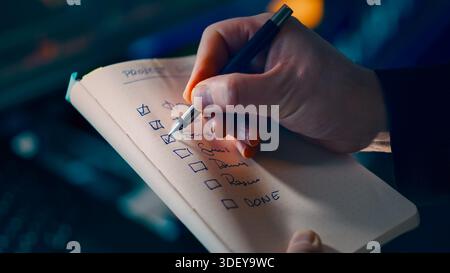 Project checklist planning productivity concept. Closeup hand writing tasks notebook pen focus workflow organization time management business efficien Stock Photo