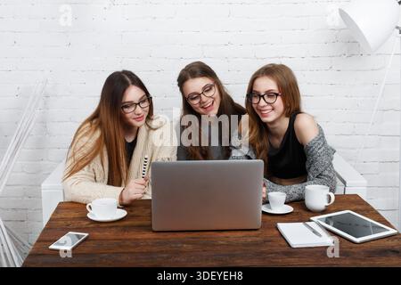 Three Friends Share a Moment While Using a Laptop in a Modern Workspace Stock Photo