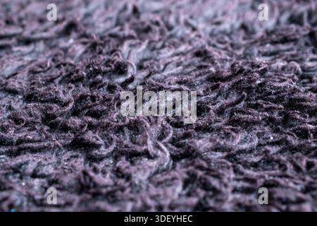 Extreme close up of deep purple synthetic rug fibers. Detailed soft hairy texture and messy pile pattern for interior decor background concept. Stock Photo
