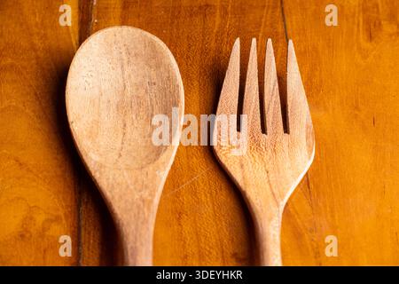 Two handmade wooden kitchen utensils placed vertically on a natural wooden surface. Minimalist eco-friendly cutlery for dining concepts. Stock Photo