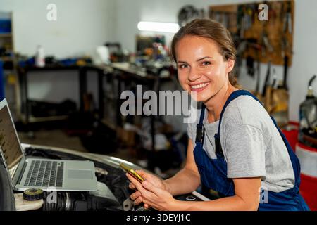Smiling female mechanic working in auto repair shop Stock Photo