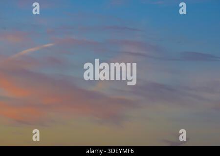 A bright and airy afternoon sky featuring a light blue atmosphere, textured white clouds, and a subtle airplane vapor trail. Stock Photo