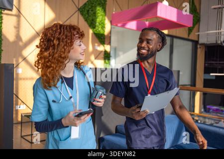 Doctors discussing patient chart on digital tablet in hospital cafeteria Stock Photo