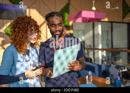 Doctors discussing patient chart on digital tablet in hospital cafeteria Stock Photo