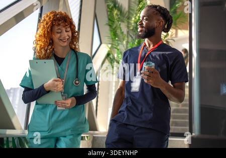 Doctors discussing patient chart on digital tablet in hospital cafeteria Stock Photo