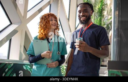 Doctors discussing patient chart on digital tablet in hospital cafeteria Stock Photo