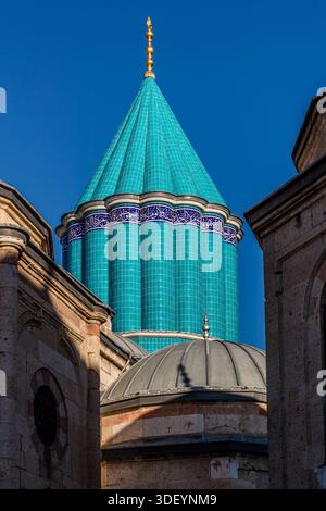 The Mevlana Museum (Mevlânâ Müzesi) in Konya's Karatay district, Turkey, shows green and gold domes and a minaret. The turquoise-tiled main dome is decorated with calligraphy. The museum is the mausoleum of the Sufi mystic Rumi (1207–1273), with an adjoining mosque and former dervish lodge; the dome, built in 1274, is considered a symbol of Konya. Stock Photo