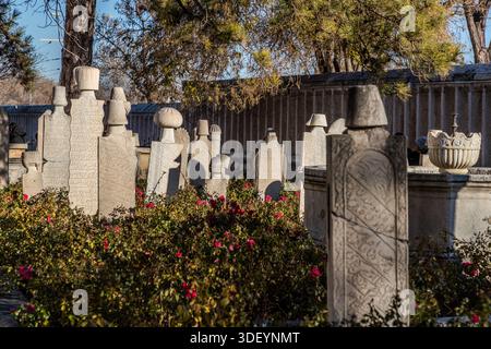 The Mevlana Museum (Mevlânâ Müzesi) in Konya's Karatay district, Turkey, shows gravestones of dervishes with Arabic calligraphy, surrounded by roses. The museum is the mausoleum of the Sufi mystic Rumi (1207–1273), with an adjoining mosque and former dervish lodge; the turquoise dome built over his grave in 1274 is considered a symbol of Konya. Stock Photo