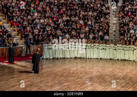 The Şeb-i Arus ceremony at the Mevlana Kültür Merkezi in Karatay, Konya, Turkey, a venue that holds up to 3,000 people, shows the Şeyh (sheikh, ceremony master) standing on the red sheepskin, with the Gözcü (overseer) in front of him ensuring the ceremony proceeds correctly. In a semicircle, the Semazenler (whirling dervishes) have taken off their Hırka (black/brown cloaks). Şeb-i Arus is the annual festival marking the death anniversary (17 December) of the mystic poet Rumi (Jalāl ad-Dīn ar-Rūmī, 1207–1273), founder of the Mevlevi order, celebrated as a spiritual union with God. Stock Photo