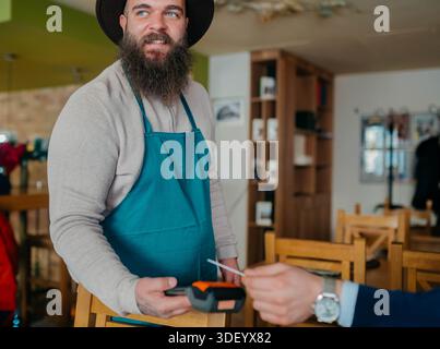 Smiling waiter taking payment from customer Stock Photo