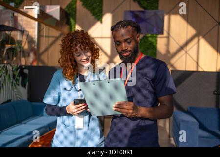 Doctors discussing patient chart on digital tablet in hospital cafeteria Stock Photo