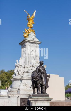 Winged Victory gilded statue and bronze man with lion on the Queen Victoria Memorial outside Buckingham Palace, London, England, UK Stock Photo
