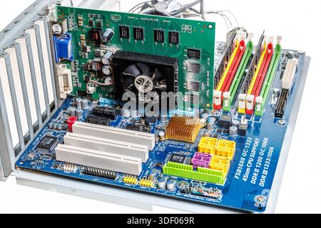 Computer main circuit board with graphics card installed, showing build up of dust around fan and components Stock Photo