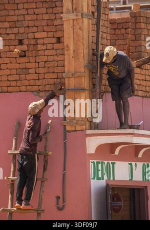 Construction workers, Behenjy, Madagascar.   Behenjy is a small town in Madagascar, located approximately 44 km south of the capital city, Antananarivo, along the RN7 national road. It is situated in the central highlands.  Woman in her shop, with her daughter. Stock Photo