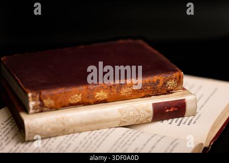 A close-up shot of two antique books stacked on top of each other, with the pages of the bottom book open. Stock Photo