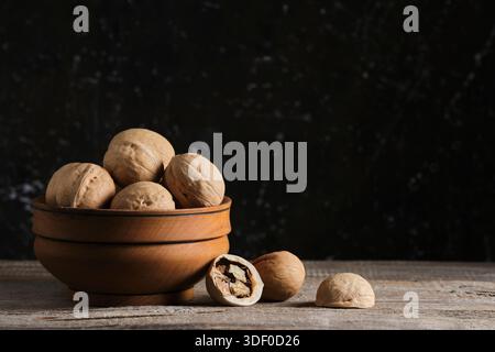 Walnuts in wooden bowl on black background. Copy space Stock Photo