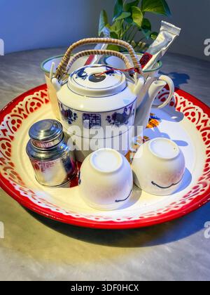 Traditional Chinese tea set ceramic teapot metal canister & cups on decorative tray placed on marble surface Sarang Paloh Heritage Stay ipoh malaysia Stock Photo