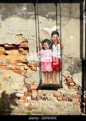 Street art mural of two smiling children on a swing painted on a weathered brick and plaster wall Stock Photo