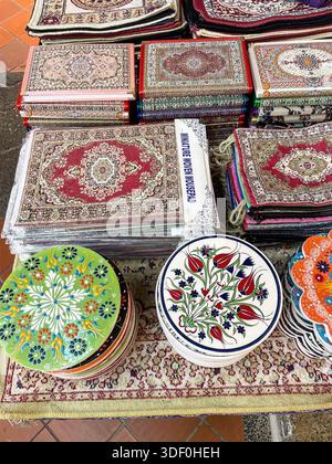 Display of colorful ceramic plates and intricately woven rugs laid out on a market stall with traditional patterns and designs Stock Photo