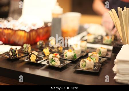 A table with many different types of sushi on small plates. The sushi is arranged in a way that makes it look like a buffet Stock Photo