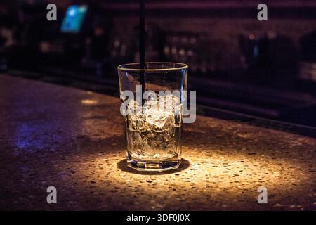 A glass of water with ice cubes in it sits on a counter. The glass is half full and the ice cubes are scattered throughout the glass. Concept of relax Stock Photo