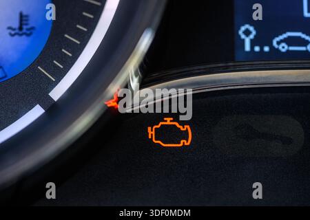 Close-up of a lit orange check engine warning light on the dashboard of a modern car. Selective focus. Stock Photo