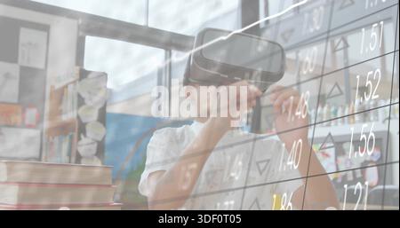 Exploring schoolboy viewing virtual stock grid in classroom, wearing white shirt and headset Stock Photo