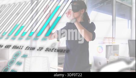 Interacting woman wearing VR headset manipulating floating data charts in open office, with laptop Stock Photo
