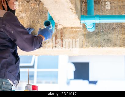 Professional Plumber Installing White PVC Drain Pipe Under Kitchen Sink in new building. Stock Photo
