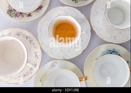 Top view of a table full of teacups on saucers with tea in the middle cup Stock Photo