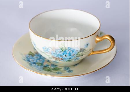 Empty teacup on a saucer, painted with blue Forget-Me-Not flowers, white background Stock Photo