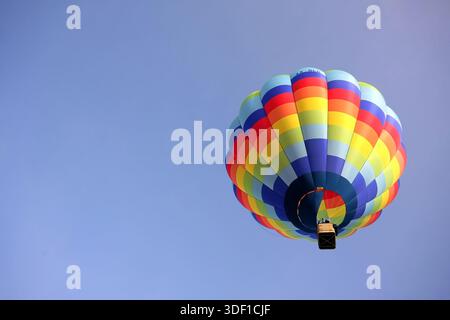 low angle view from inside a colorful hot air balloon looking up at the vibrant fabric panels and the wicker basket suspended above beatiful rainbow Stock Photo