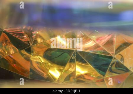 Abstract reflective faceted surface with shiny golden and colorful geometric triangles creating futuristic texture and artistic luxury pattern with br Stock Photo