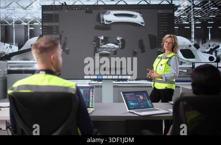 Diverse Team Of Engineers Collaborate On Electric Car Design In Meeting. Stock Photo