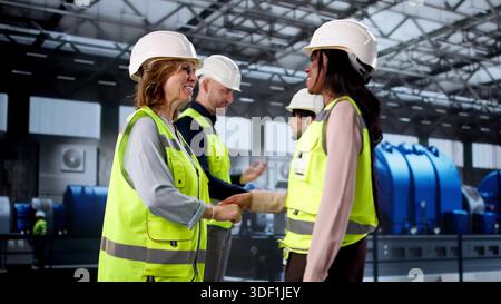Workers Of Diverse Backgrounds Shaking Hands At Power Plant Facility. Stock Photo