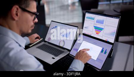 Young Latino Consultant Using Laptop To Analyze Business Data In Office. Stock Photo