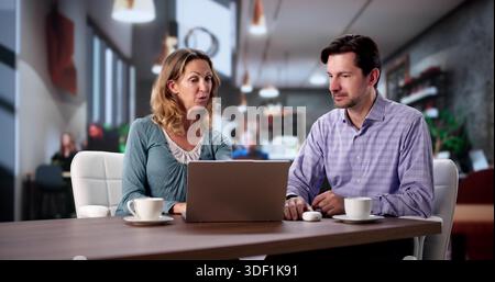 Coworkers Sipping Coffee And Working On Laptops In Shared Office. Stock Photo