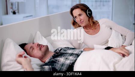 Female Counselor Using Headphones To Cancel Snoring In Marriage Stock Photo