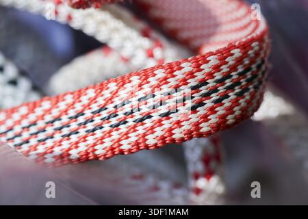 Close up colorful woven nylon cord texture detail with red white and black diagonal zig zag pattern showing intricate weaving technique and durable sy Stock Photo