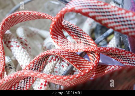 Detailed closeup of tangled red white woven synthetic webbing texture showing strong nylon strap material pattern used for industrial safety equipment Stock Photo