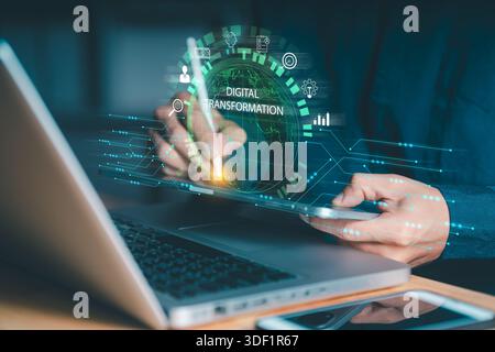 Person interacting with a tablet and laptop, featuring a glowing "DIGITAL TRANSFORMATION" sphere and business icons. Symbolizes applying technology fo Stock Photo