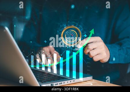 A person interacts with a laptop, Holographic display featuring a bar graph and an upward-trending line graph, symbolizing business growth and data an Stock Photo