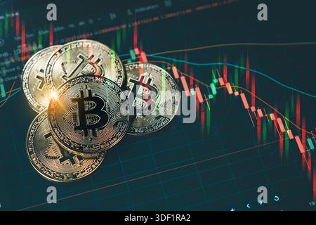 A shiny gold Bitcoin coin stacked on other coins, set against a dark background with red and green candlestick charts illustrating a volatile cryptocu Stock Photo