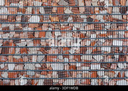 Background made of broken bricks and stone pieces behind metal lattice. Stock Photo