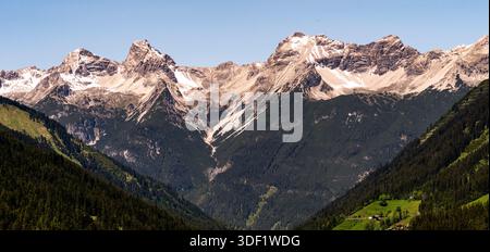Panoramic view of snow-capped mountain range under clear blue sky. Stock Photo