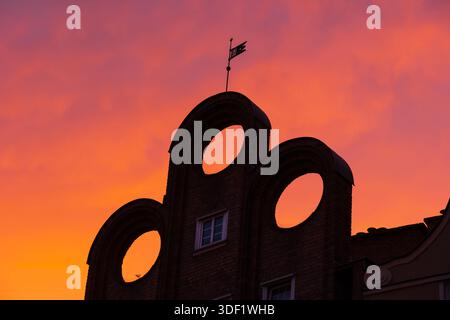 Unique gable of historic tenement house with three holes and attic window against sunset sky in Old Town of Gdansk in Poland. Stock Photo