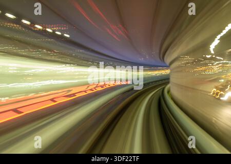 View of blurred light streaks, creating an illusion of speed through a tunnel, illuminating the curved tracks ahead, Tokyo, Tokyo, Japan. Stock Photo